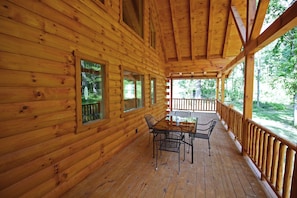 Une cabane en bois dotée d’un porche abrité, d’une table à manger et de chaises.
