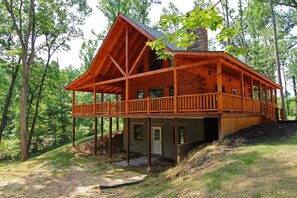 A wooden cabin with a balcony, surrounded by trees.
