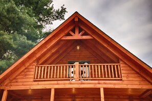 Een houten chalet met balkon en een puntdak.