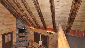 A cozy cabin interior with a stone fireplace, wooden beams, and a comfortable seating area. - Kalli's Luxury Retreat- Unique Couple's Cabin (Logan)