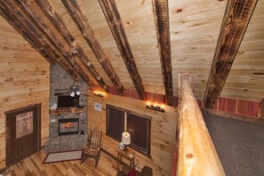 Ein gemütliches Blockhaus-Interieur mit Kamin aus Stein, Holzbalken und einer komfortablen Sitzecke.