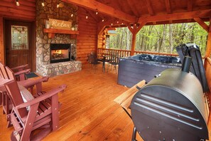 Une terrasse en bois avec un foyer en pierre, des sièges d’extérieur et un barbecue.