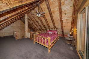 A wooden bedroom with a sloped ceiling, a wooden bed, a small bedside table, and a ceiling fan. - Kalli's Luxury Retreat- Unique Couple's Cabin (Logan)