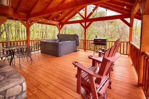 Une terrasse en bois avec un jacuzzi, un barbecue et des meubles pour se détendre en plein air.