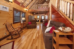 A cozy cabin interior with wooden walls, a loft bedroom, a dining area, and a kitchen. - Kalli's Luxury Retreat- Unique Couple's Cabin (Logan)