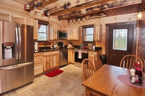 Una cocina moderna con muebles de madera, electrodomésticos de acero inoxidable y un comedor con mesa y sillas de madera.
