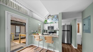 Una cocina moderna con una isla integrada, electrodomésticos de acero inoxidable y una puerta corrediza de vidrio que da a una terraza.