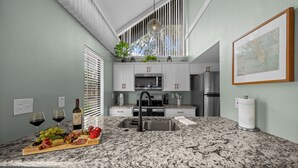 Una cocina moderna con encimera de granito, electrodomésticos de acero inoxidable y una botella de vino.