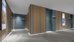 A modern hotel lobby with a minimalist design, featuring a long corridor with doors, recessed lighting, and framed artwork on the walls. - Haiyi Fino Hotel (Jingmen)