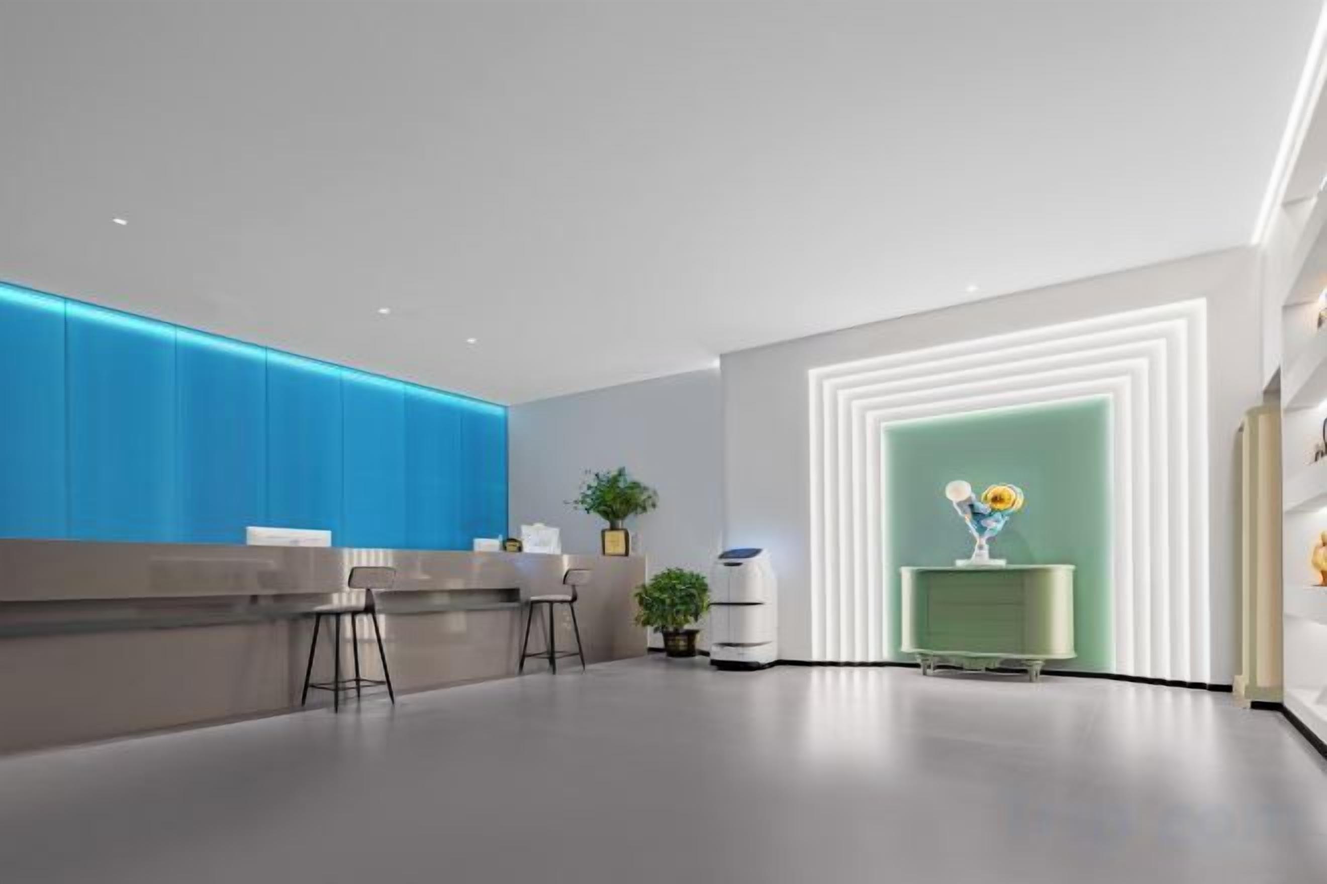 A modern reception area with a counter, seating, and a decorative plant.