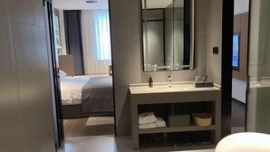 A modern hotel room with a large bed, a bathroom with a vanity and mirror, and a view of the city through the window. - Haiyi Fino Hotel (Jingmen)