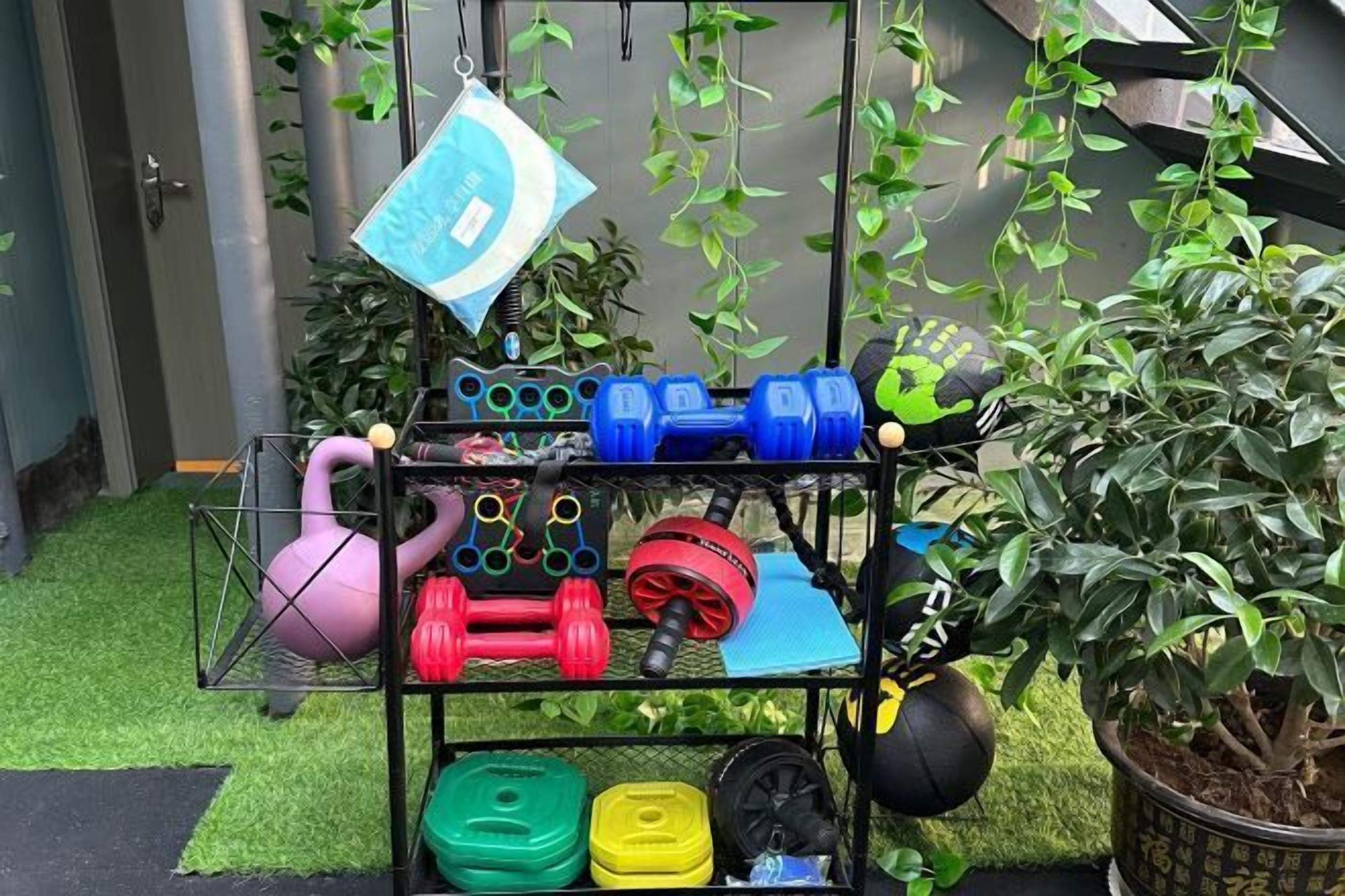 A home gym setup with various exercise equipment including dumbbells, kettlebells, and a yoga ball.