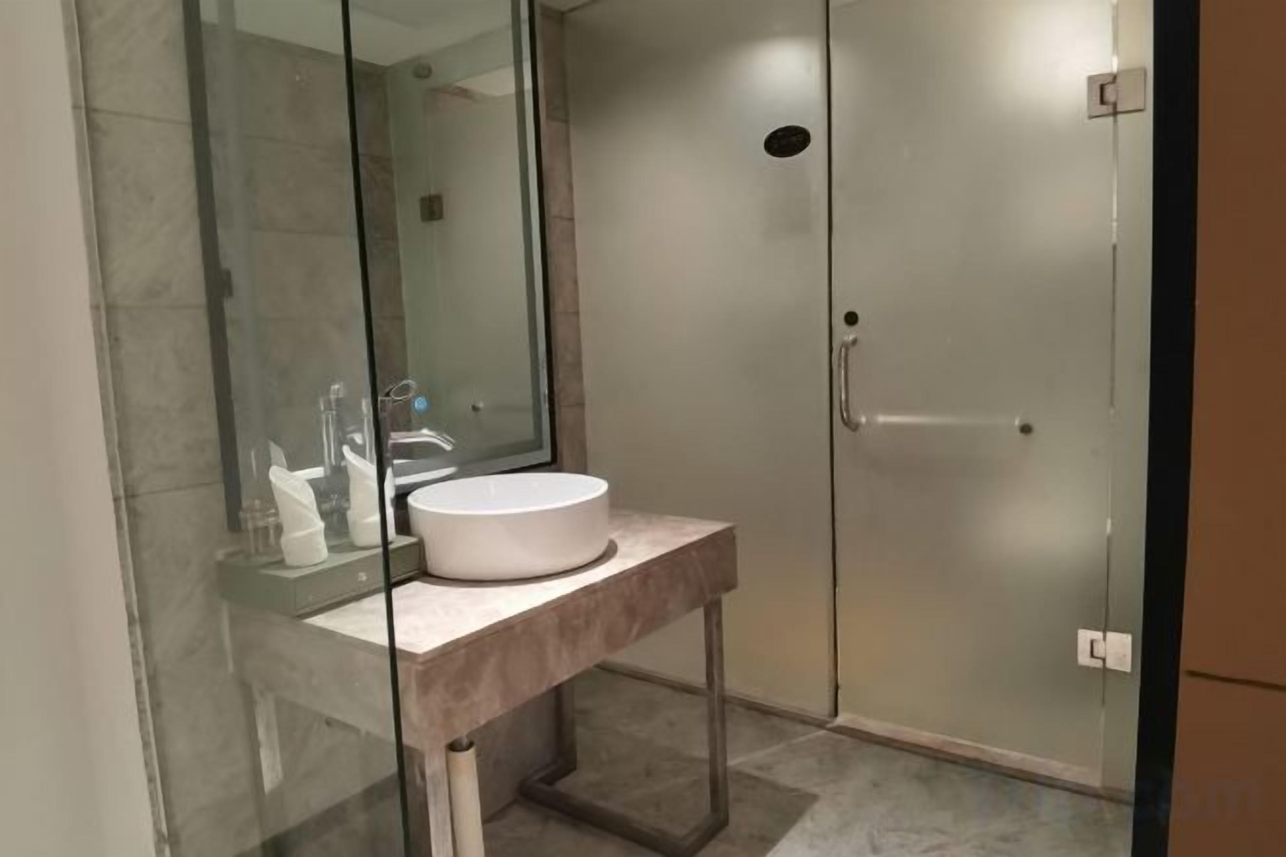 A modern bathroom with a glass-enclosed shower, a white sink, and a marble countertop.