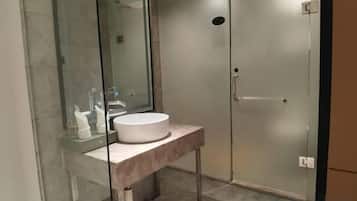A modern bathroom with a glass-enclosed shower, a white sink, and a marble countertop.