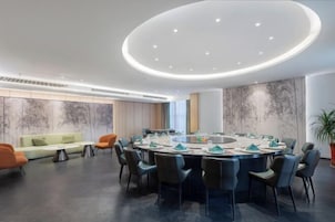 Una sala de conferencias moderna con una mesa redonda, sillas negras y un sofá de color claro.