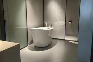 Um banheiro moderno com banheira independente, design minimalista e paredes de vidro fosco.