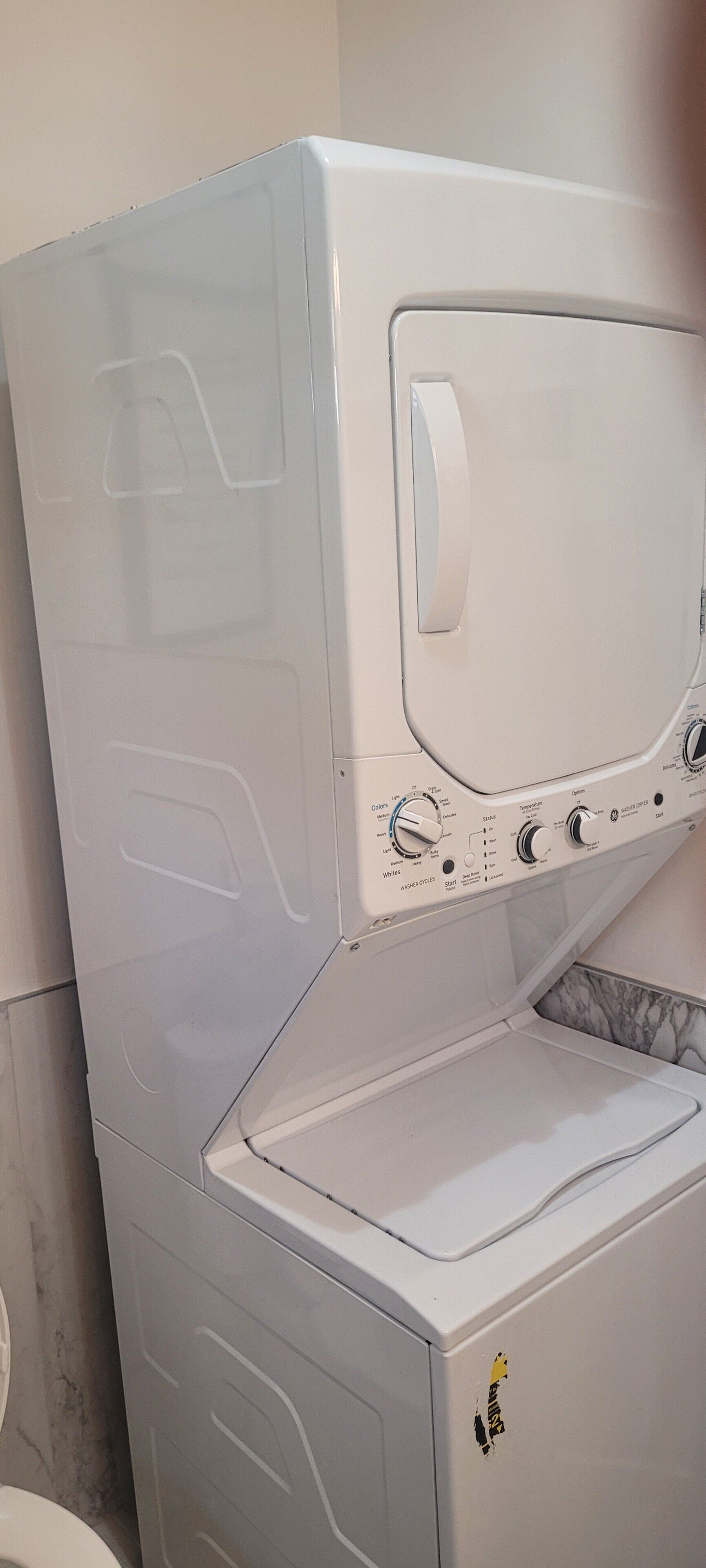 Vue de face d’un lave-linge blanc, avec des boutons de commande et un petit autocollant sur le côté droit.
