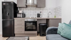A compact kitchen with a refrigerator, oven, and toaster. - Roof Terrace | W/M | Smart TV | Free Parking (Old Swan)