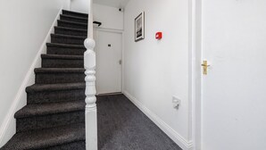 Un escalier dont les marches sont recouvertes de moquette et une porte blanche au sommet.