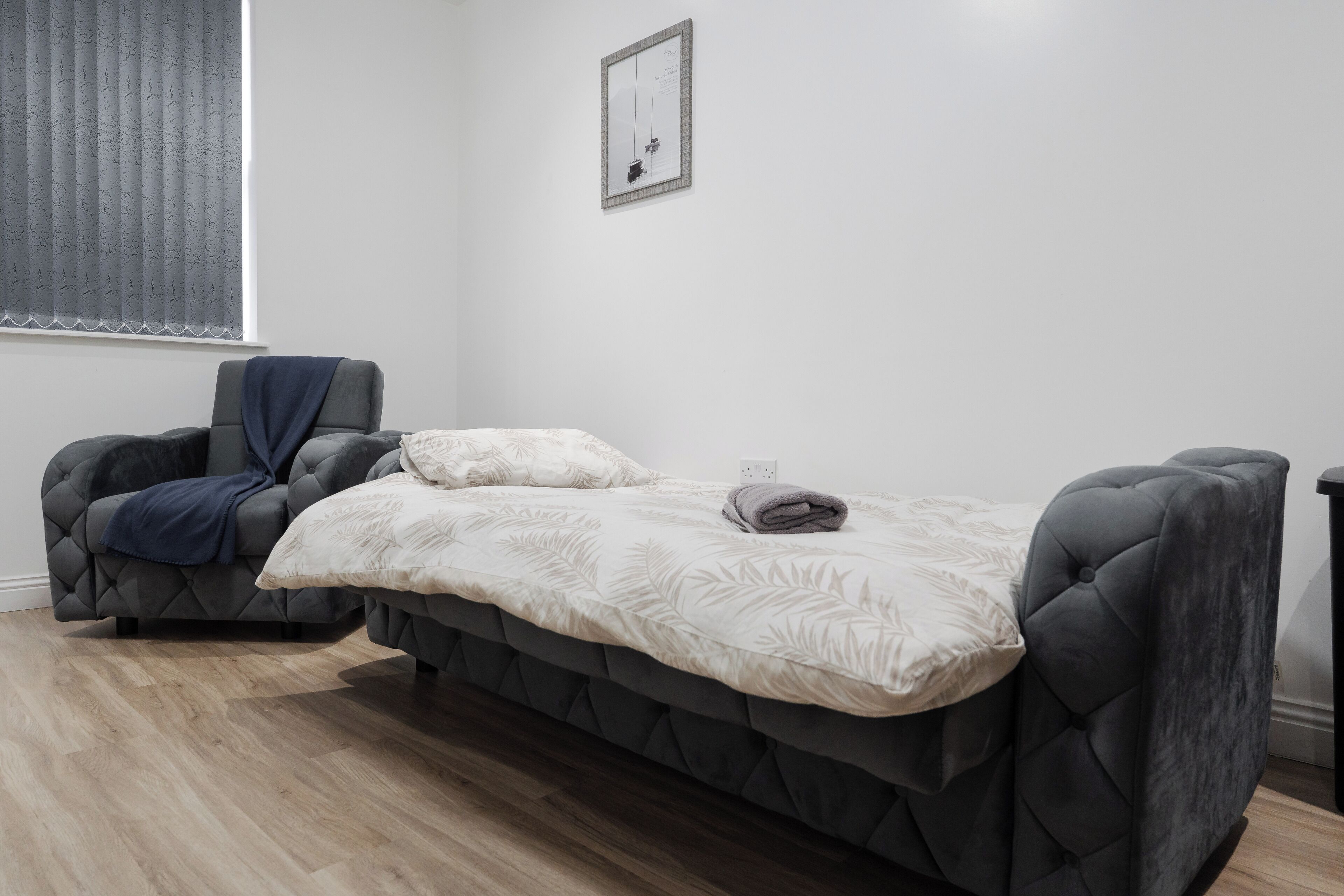 Une chambre moderne avec un lit, une chaise et une fenêtre équipée de stores.