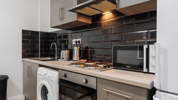 Una cocina moderna con estufa de acero inoxidable, microondas y horno empotrado.