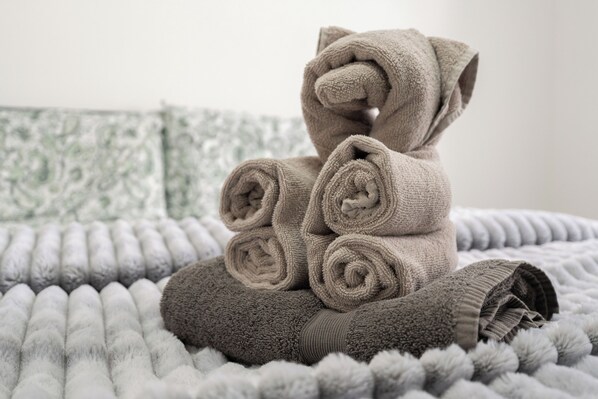 A neatly folded towel sculpture resembling a bear on a textured bed.
