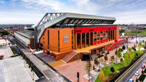 A stadium with a distinctive architectural design, featuring a prominent red facade and a large entrance.