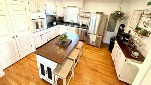 A modern kitchen with white cabinetry, a central island, and a stainless steel refrigerator.