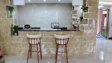 Una cocina con salpicadero de mármol, dos taburetes de bar y una encimera con una planta pequeña y un reloj.