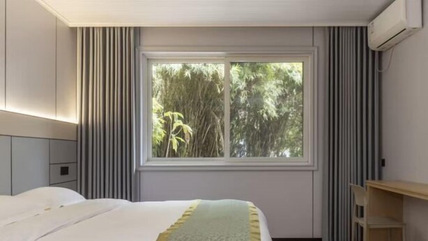 A bedroom with a bed, a desk, and a window with curtains. - Labor Model Resort (Shanghai)