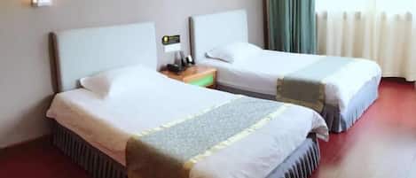 A hotel room with two beds, a nightstand, a lamp, and artwork on the wall.