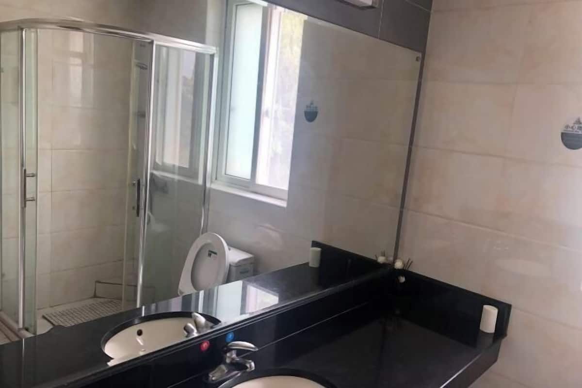 A bathroom with a glass shower enclosure, a sink with a mirror, and a toilet.