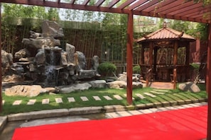 A garden with a rock waterfall, a gazebo, and a red carpet path. - Labor Model Resort (Shanghai)