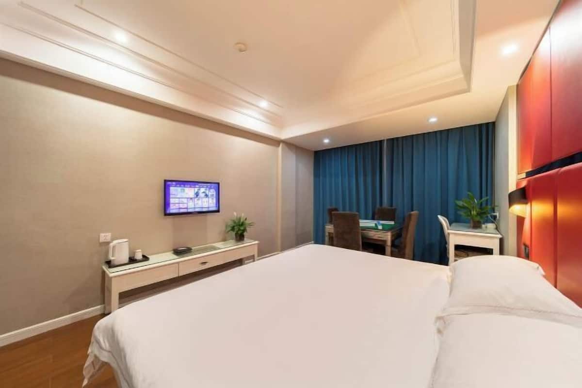 Une chambre d’hôtel comprenant un lit, un bureau avec un ordinateur, une télévision et un coin repas avec des chaises et une table.
