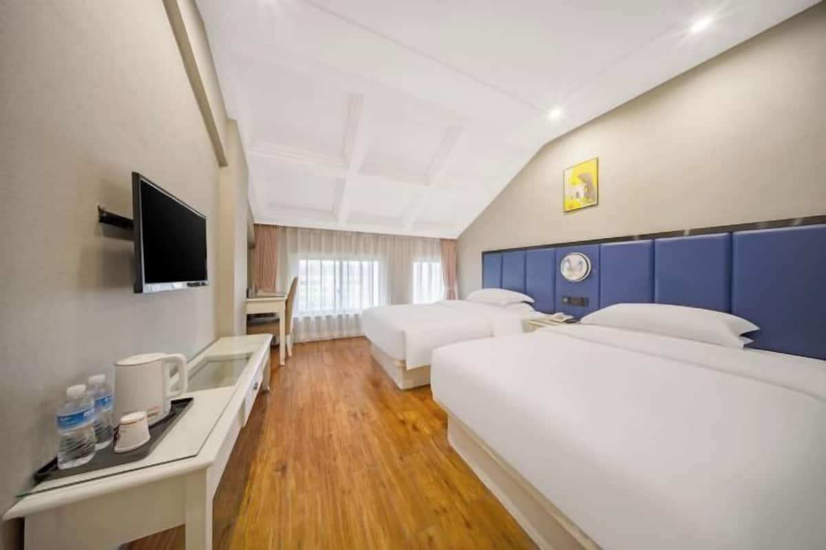 Une chambre d’hôtel avec deux lits, un bureau doté d’un téléviseur à écran plat, une machine à café et une fenêtre avec des rideaux.