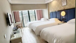Habitación de hotel con dos camas, televisión, escritorio y vista a la ciudad.