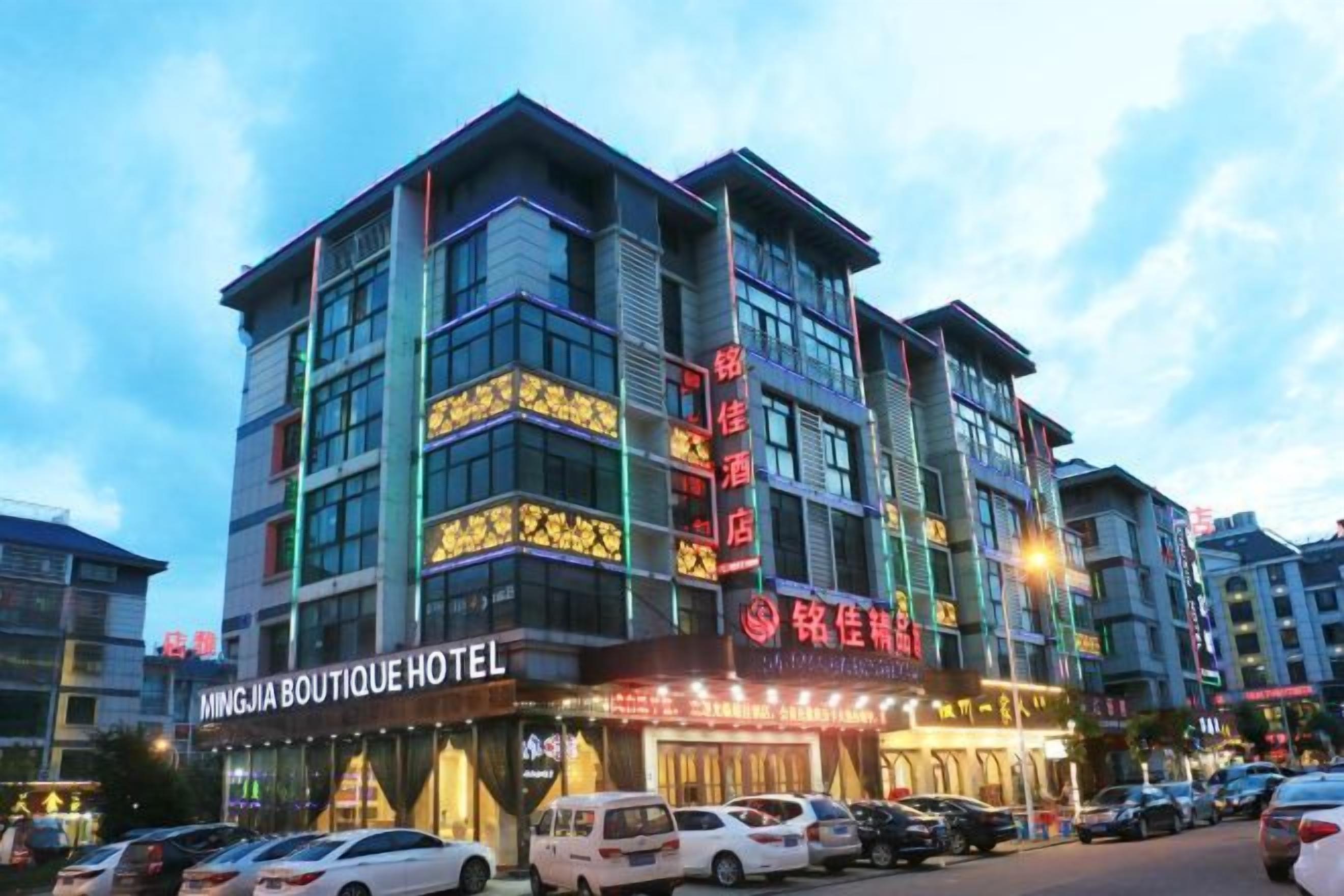 A multi-story hotel with signage for 'MINGJIA BOUTIQUE HOTEL' and 'SHENGHUI HOTEL'.