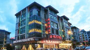 A multi-story hotel with signage for 'MINGJIA BOUTIQUE HOTEL' and 'SHENGHUI HOTEL'.