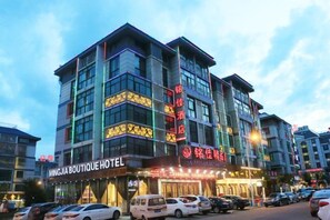 Un hotel de varios pisos con letreros que indican 'MINGJIA BOUTIQUE HOTEL' y 'SHENGHUI HOTEL'.
