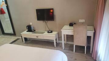 A hotel room with a bed, a desk, a chair, a television, and a mirror.