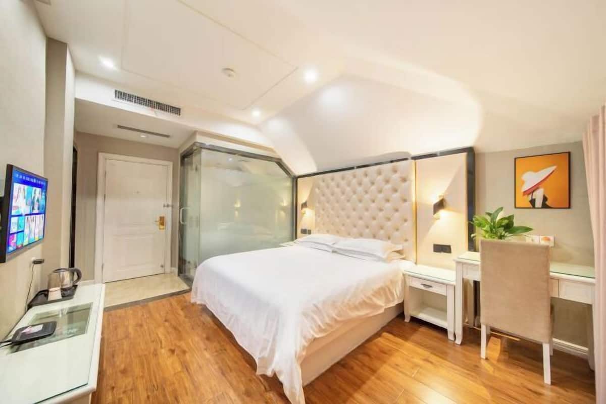 Une chambre d’hôtel équipée d’un lit, d’une table de chevet, d’une chaise, d’un bureau et d’un téléviseur fixé au mur.