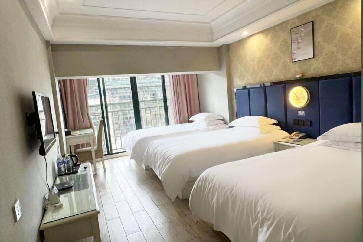 Une chambre d’hôtel avec deux lits, une table en verre, un téléviseur et une vue sur la ville.