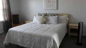 Een slaapkamer met een groot bed, een stoel, een nachtkastje en een verwarming.