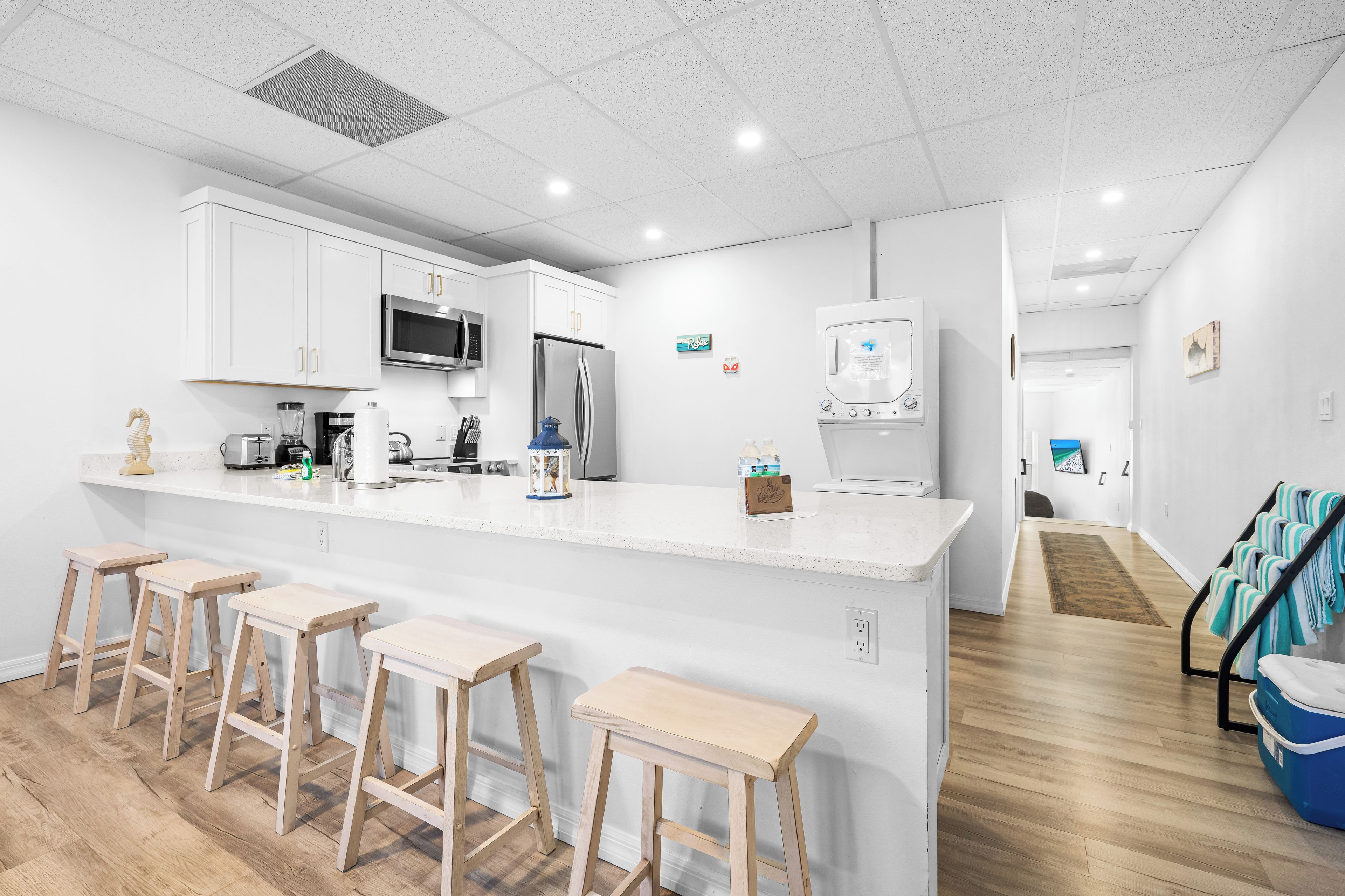 A modern kitchen with white cabinetry, stainless steel appliances, and a bar area with stools.