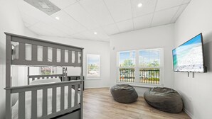 A child's room with a bunk bed, two bean bags, and a TV on the wall. - Mallory Squared (Siesta Key)