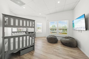 A child's room with a bunk bed, two bean bags, and a TV on the wall. - Mallory Squared (Siesta Key)