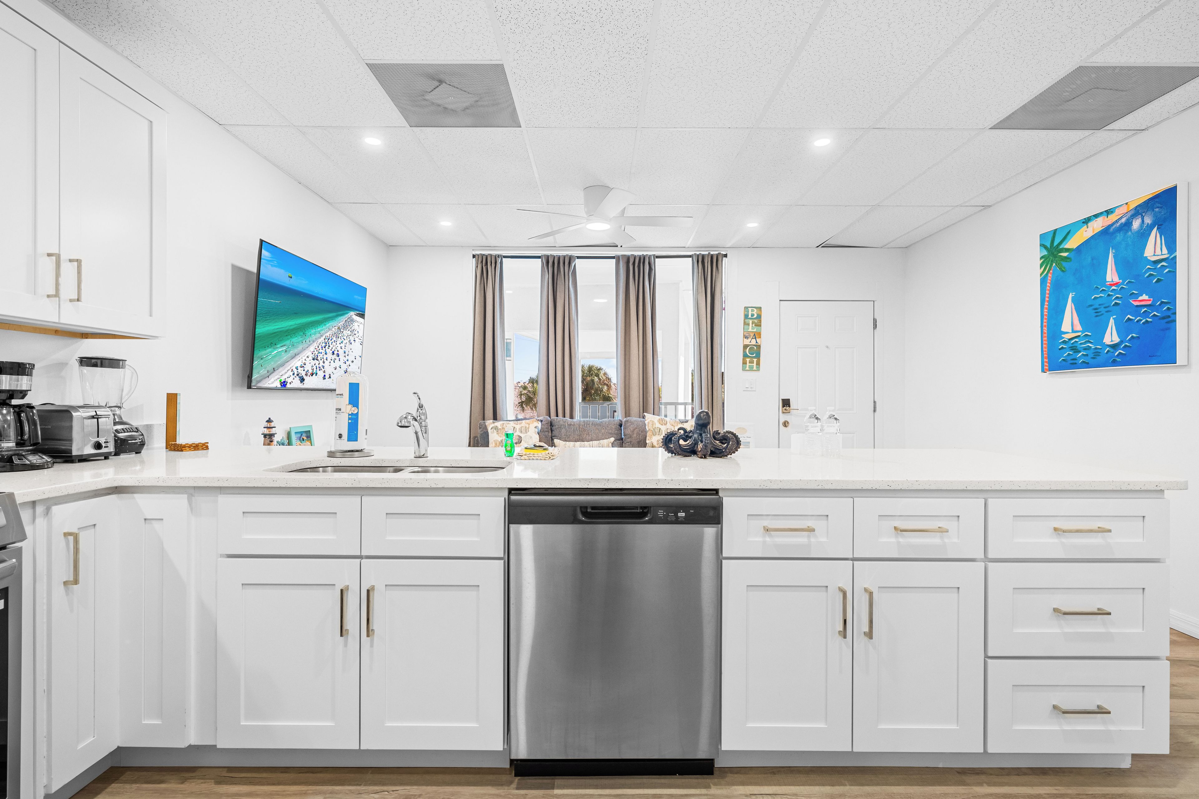 A modern kitchen with white cabinetry, a stainless steel dishwasher, and a large island with a sink.