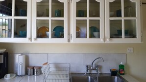A kitchen with white cabinets, a stainless steel sink, and a dish rack.
