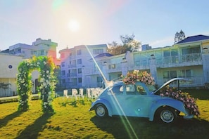 A vintage car with a floral arrangement, a grassy area, and a building with balconies in the background. - Shenzhen Xiyong Resort (Shenzhen)