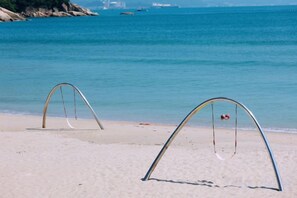A beach with two metal swing structures and a calm sea in the background. - Shenzhen Xiyong Resort (Shenzhen)